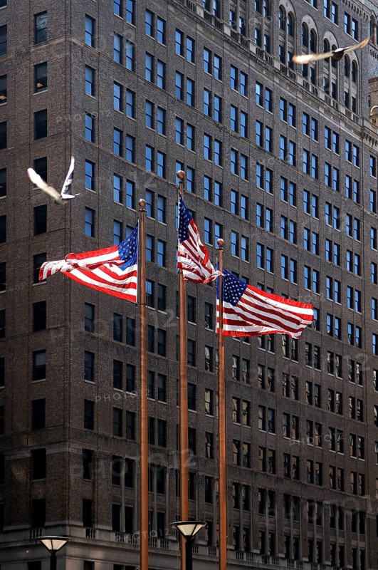Waving US flags in front of a skyscraper, New York City, USA