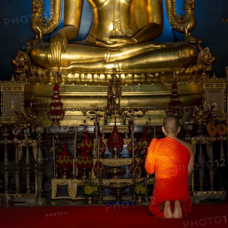 Monk meditating in front of the Phra Buddha Chinnarat, Buddha statue with Bhumispara-mudra, Buddha Gautama at the moment of enlightenment, Wat Benchamabophit, also: marble temple, Dusit district, Bangkok, Thailand