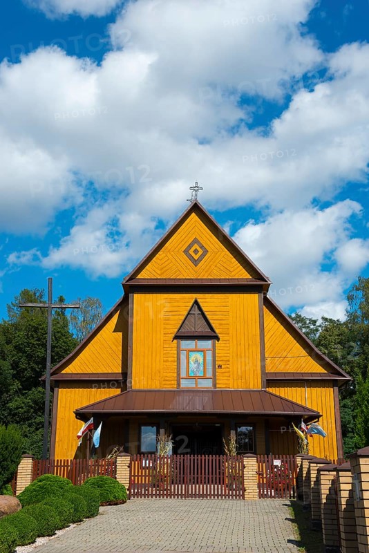 Yellow wooden church with blue sky in the background, surrounded by trees in summer, Church of the Holy Apostles Peter and Paul, Olbiecin, Olbiecin, Powiat Krasnik, Krasnik, Lublin Voivodeship, Poland