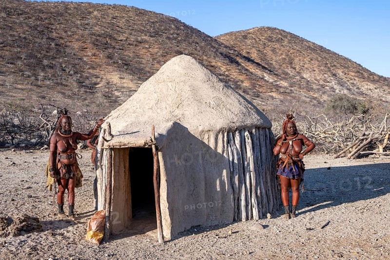 Married Himba woman leaning against a traditional mud house, traditional Himba village, Kaokoveld, Kunene, Namibia