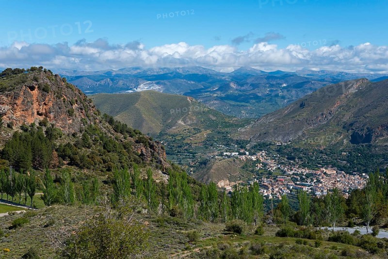 Panoramic landscape with mountains, a valley and a village, surrounded by greenery and under a clear sky, mountain village Güéjar Sierra, Güejar, Granada province, Andalucia, Spain