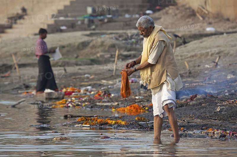 Indian man washing linen in polluted water of the Ganges river at Varanasi, Uttar Pradesh, India