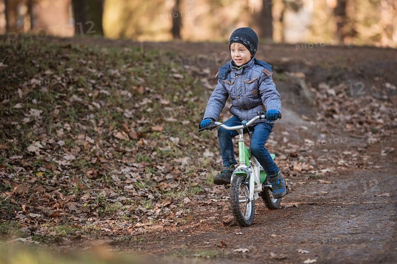 Six years old boy rides bicycle from the hill in the park