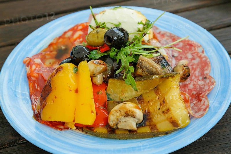 Mediterranean cuisine, grilled vegetables arranged on plates, mushrooms, mushrooms, red and yellow peppers, rocket, salami, black and green olives, Italian starter, antipasto misto, healthy cuisine, food photography, studio, Germany