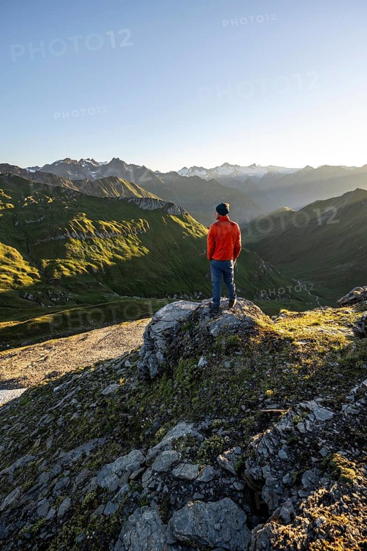 Mountaineer in front of mountain landscape at sunrise, view of mountain peaks of the Venediger group and into the Großbachtal valley from the summit of Bachlenkenkopf, Lasörling group, Hohe Tauern National Park, East Tyrol, Tyrol, Austria