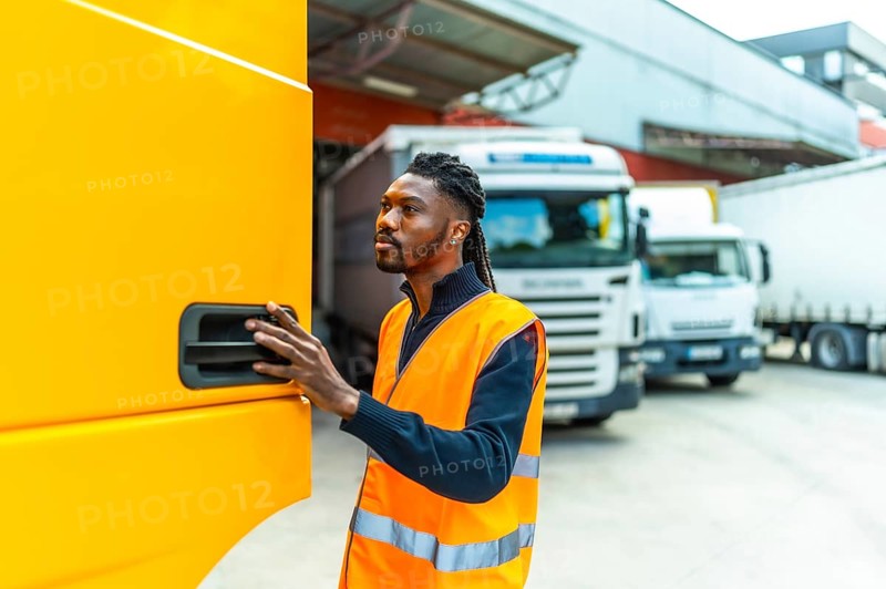 African driver opening the door of a truck to enter in a distribution warehouse