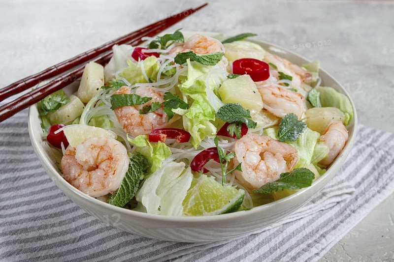 Thai salad with shrimp and rice noodles, pineapple slices, coriander and mint leaves, on a white plate, homemade, no people