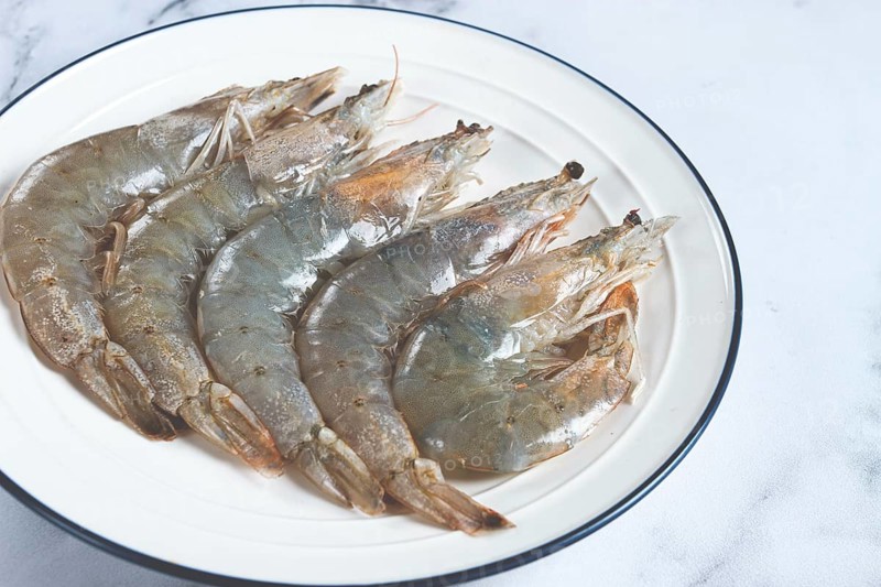 Fresh raw white-footed shrimp, tiger prawns vannamei, on a white plate