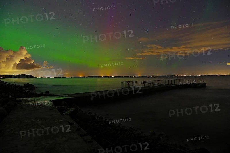 Northern lights over a quiet fjord at night, with clouds on the horizon, Tönsberg, Oslofjord, Norway