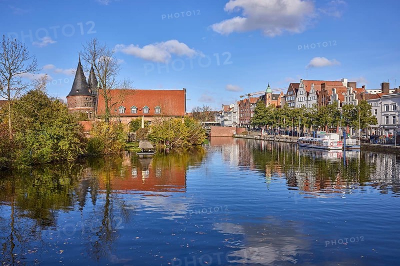 River Trave, Holstentor, historic salt warehouse, trees, blue sky with fair weather clouds, reflections on the water surface, Hanseatic city of Lübeck, independent city, Schleswig-Holstein, Germany