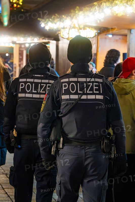 Two policemen at a busy Christmas market at night, Christmas market Ludwigsburg, Germany