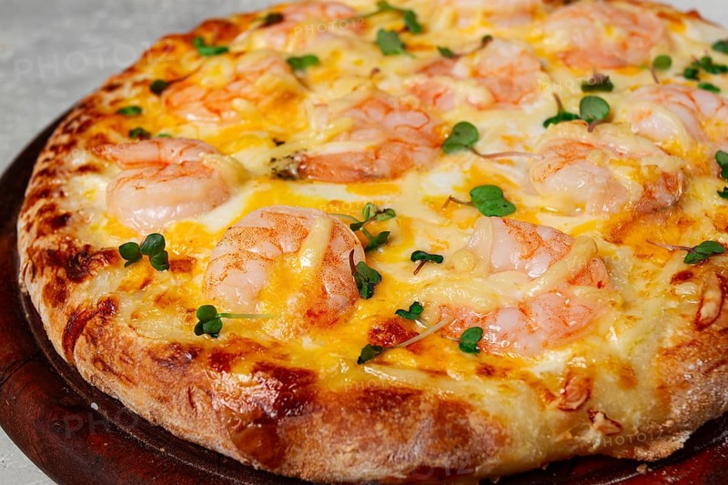 Four cheese pizza with shrimp and fresh microgreens, served on a wooden board, homemade, no people