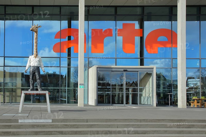 Entrance to the modern building of the ARD and ZDF broadcasting station Arte with sculpture Giraffe Man by Stephan Balkenhol, modern art, giraffe figure, giraffe man, animal figure, male figure, mythical creature, inscription, glass wall, television station, broadcasting, modern, Strasbourg, Bas-Rhin, Alsace, France