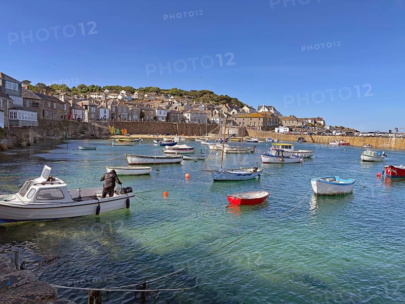 Scene in a busy harbour with people swimming and paddling in the water, Mousehole, Cornwall, Great Britain