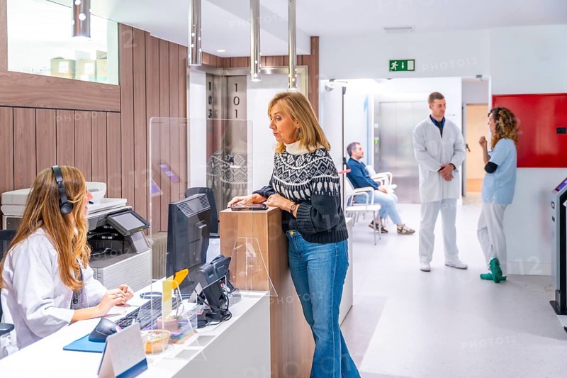 Entrance of the hospital with patient in the reception attended by a woman next to people around