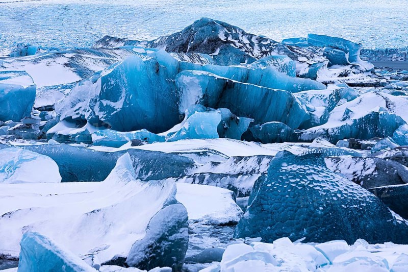 Snow-covered icebergs in the glacier lagoon Jökullsarlon, Breidamerkurjökull in the background, Sudurland, Iceland