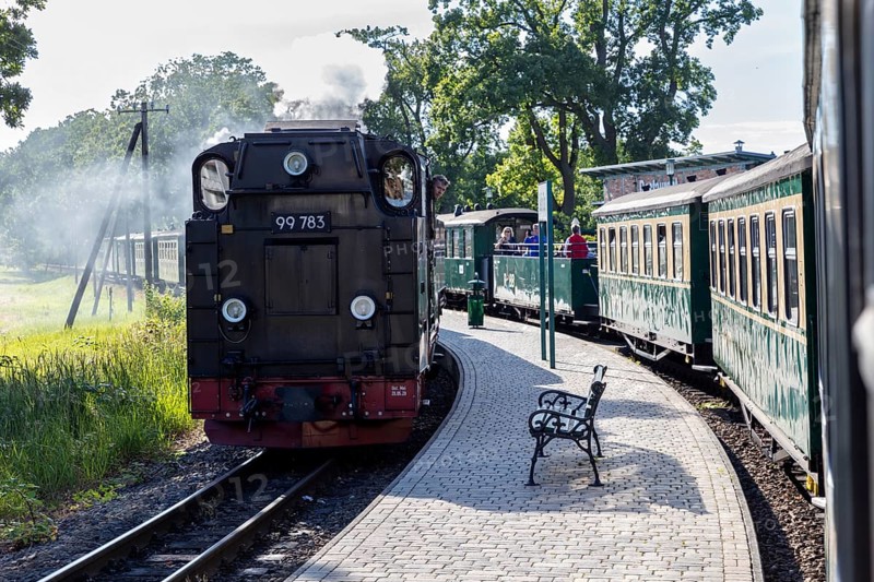 A steam locomotive pulling wagons, shot from behind on a sunny platform, Rügen, Rasender Roland