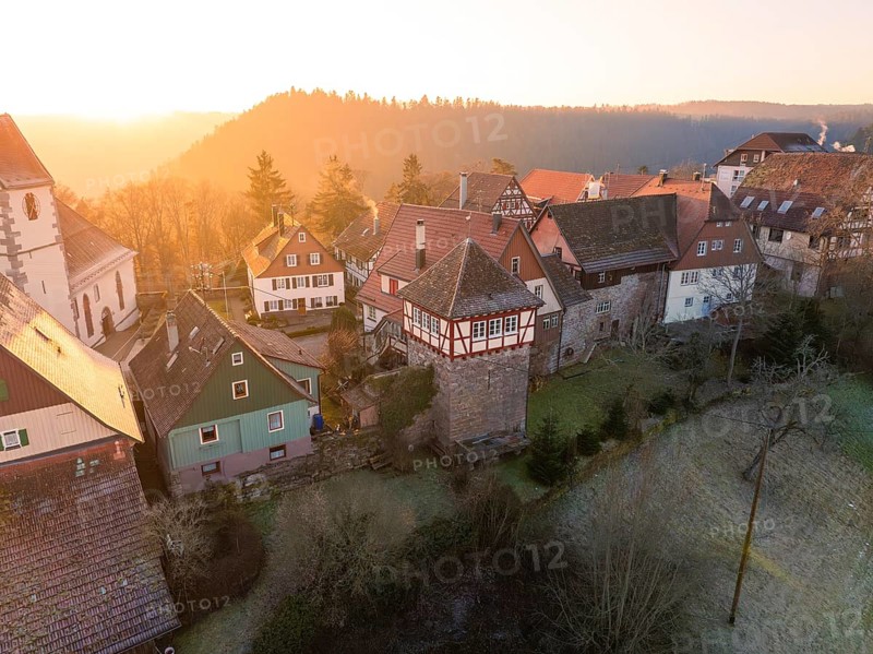 A village with half-timbered houses and a historic tower in wintry surroundings at sunset, Zavelstein, district of Calw, Black Forest, Germany