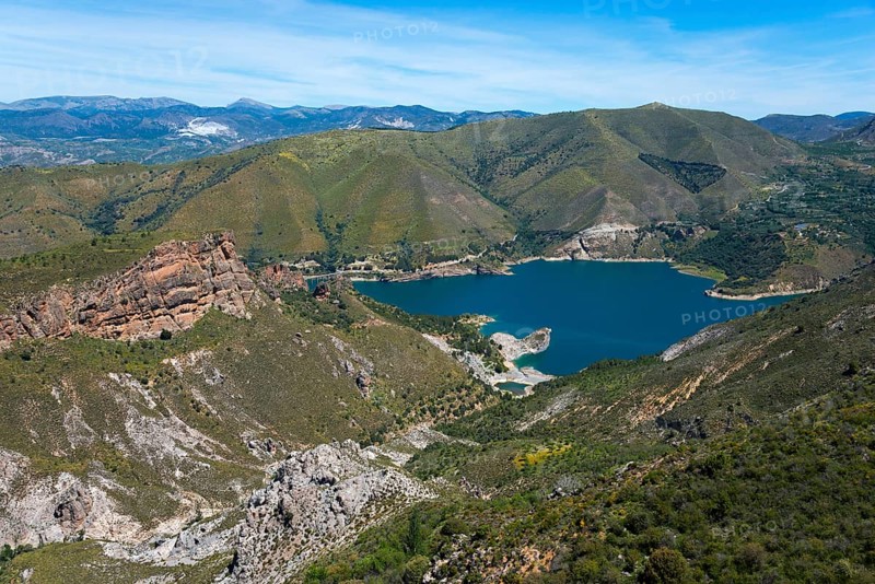 Panoramic view of a blue lake surrounded by green mountains and rocks under a clear sky, reservoir, Embalse de Canales, Canales dam, Sierra Nevada, near Güéjar Sierra, Granada province, Andalusia, Spain