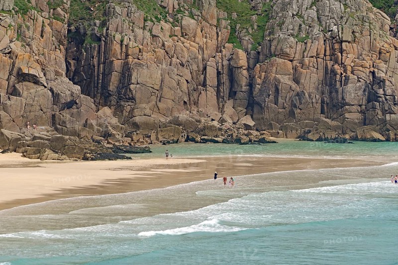 Sandstrand mit hohen Klippen und ruhigem türkisfarbenem Meer, wenige Menschen, Porthcurno, St Levan, Cornwall, Großbritannien