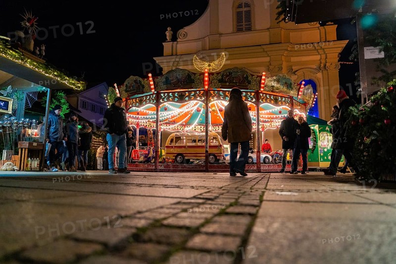 An illuminated carousel with people surrounded by a nocturnal city atmosphere, Christmas market Ludwigsburg, Germany
