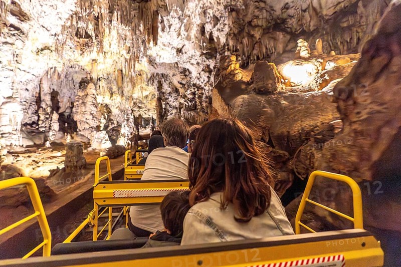 Tourists enjoying a train ride through the magnificent formations of postojna cave, a popular destination in slovenia