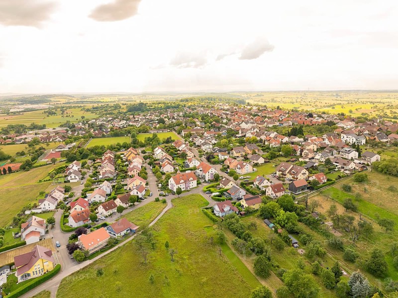 Densely built-up residential area with houses and gardens, surrounded by fields under a cloudy sky, Kieselbronn, Germany