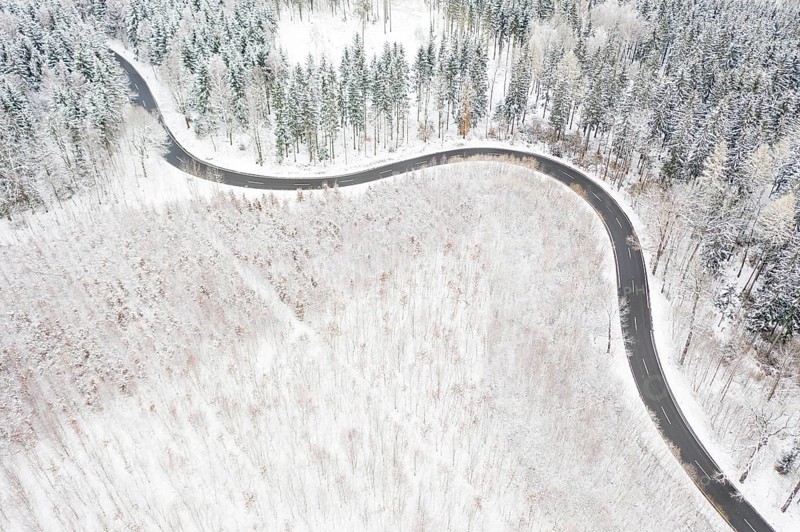 Aerial view of a winding country road and forest in the snow, between Eppendorf and Leubsdorf, Central Saxony, Germany
