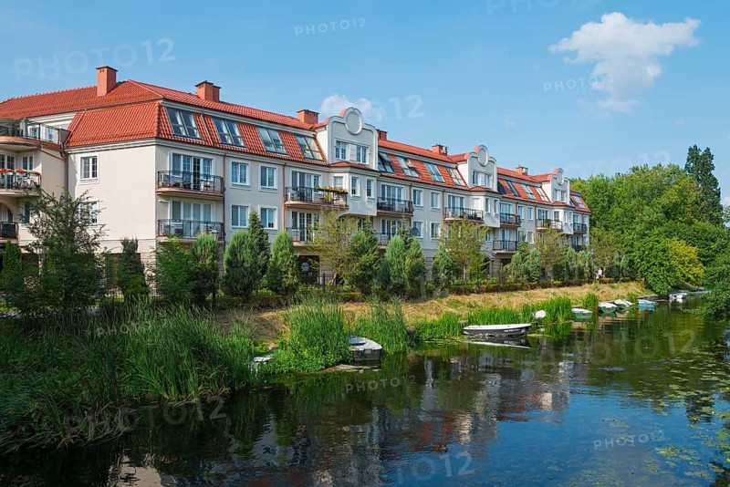 Modern residential buildings on a quiet riverbank with small boats and lush greenery in a summery ambience, Elk, Elk, Lyck, Elk River, Warmia-Masuria, Poland