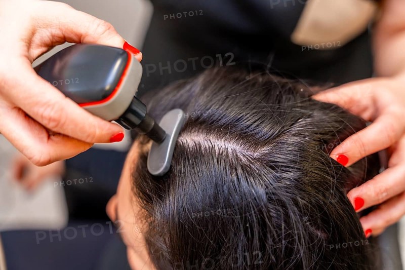 Top view close-up of a woman receiving modern treatment to combat hair loss using Indiba machine