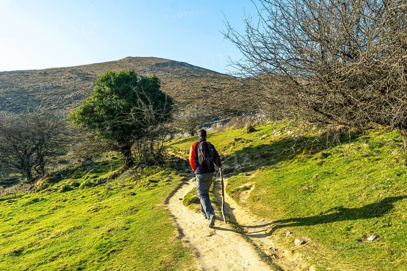 A man walking on the path climbing to the top of Mount Ernio or Hernio in Gipuzkoa, Basque Country