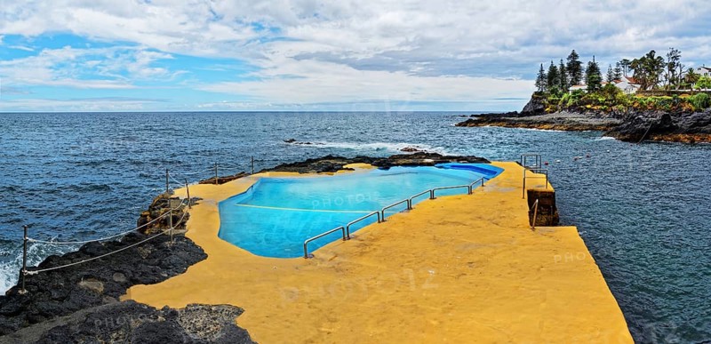 Natural swimming pool on rocks overlooking the ocean and cliffs under a cloudy sky, Caloura, Ribeira Chã, Sao Miguel Island, Azores, Portugal