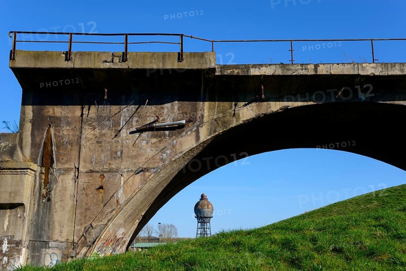 Old concrete bridge in front of a blue sky with a water tank in the background, surrounded by meadow, spherical water tower, landmark, Ilseder Hütte, Ilsede, district of Peine, Lower Saxony, Germany