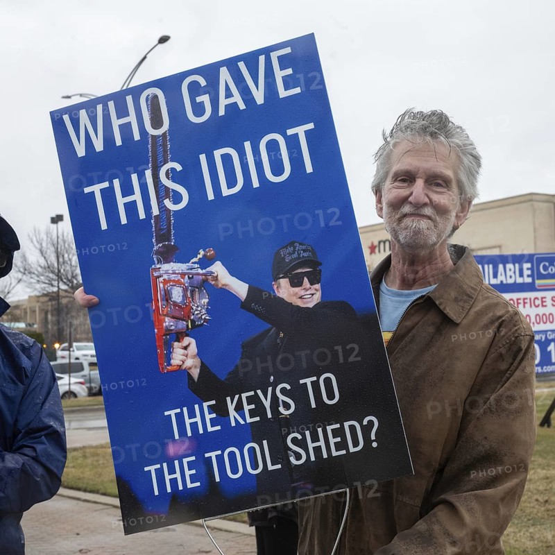 Troy, Michigan USA - 29 March 2025 - People gathered in the rain outside the Tesla Showroom at the Somerset Mall to protest Tesla owner Elon Musk's role in slashing government services. It was one of many 'Tesla Takedown' actions planned around the country and abroad