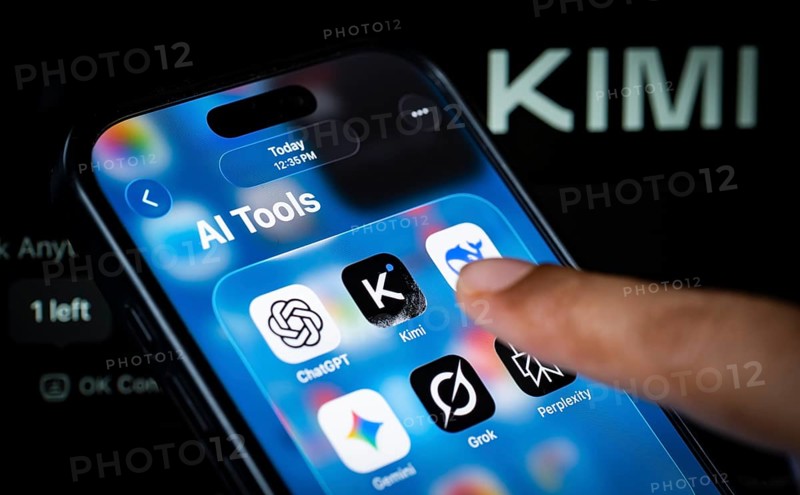 In this photo illustration, a person uses the Kimi AI chatbot on a smartphone while the KIMI logo is displayed on a screen in the background, in New Delhi, India on 20 November 2025. Kimi AI is a Chinese artificial intelligence chatbot and assistant developed by Moonshot AI, a fast-growing tech company in China