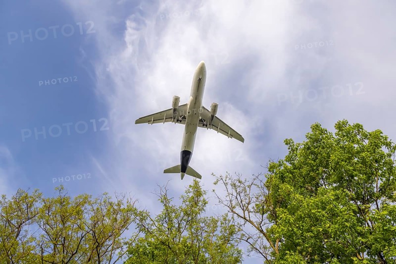 Aeroplane on approach shortly in front of landing at Frankfurt Airport, Fraport. The aeroplane as a silhouette above trees. Frankfurt am Main, Hesse, Germany