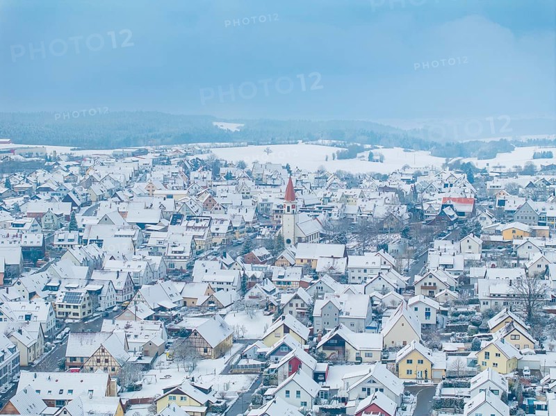Town in winter with snow-covered roofs and a central church tower, Deckenpfronn, Böblingen district, Germany