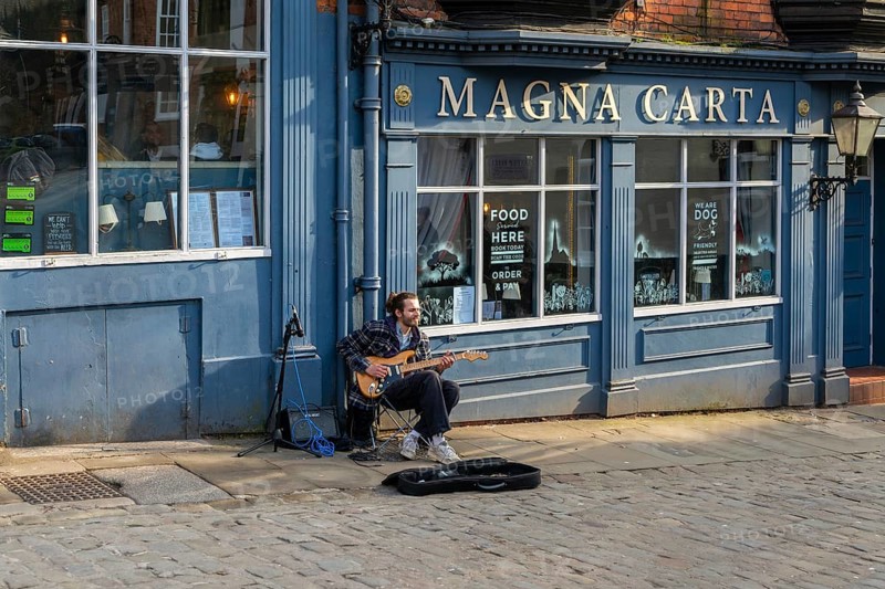 Musician guitarist busking outside Magna Carta pub, Castle Hill, city of Lincoln, Lincolnshire, England, UK
