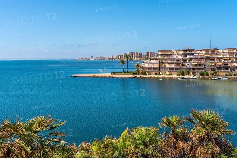 Captivating cityscape of la manga during summer, featuring a serene blue sea, swaying palm trees, and a picturesque coastal view, Cala del Pino