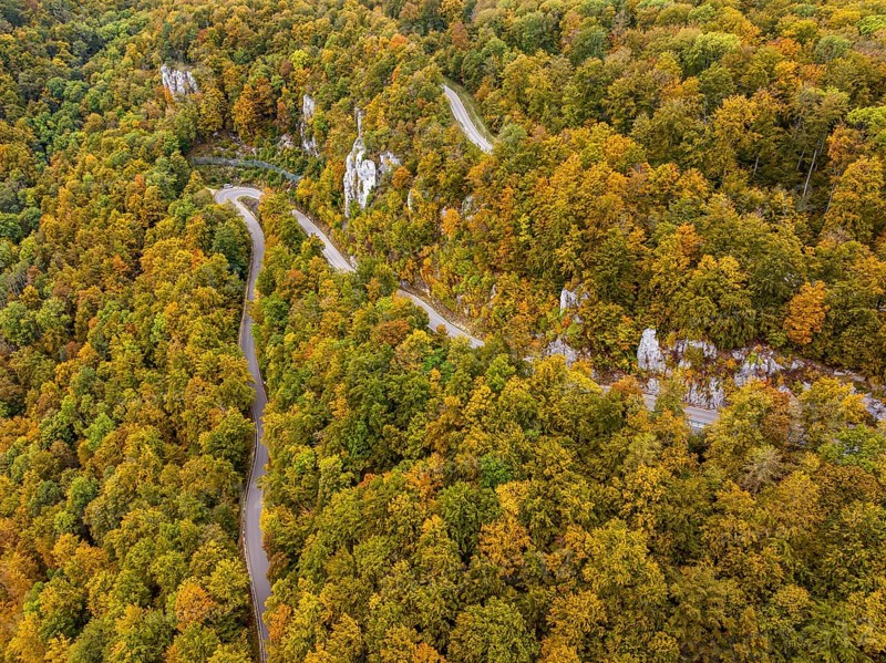 Swabian Alb in autumn, Albtrauf with colourful mixed forest and winding country road. Bad Urach, Baden-Württemberg, Germany