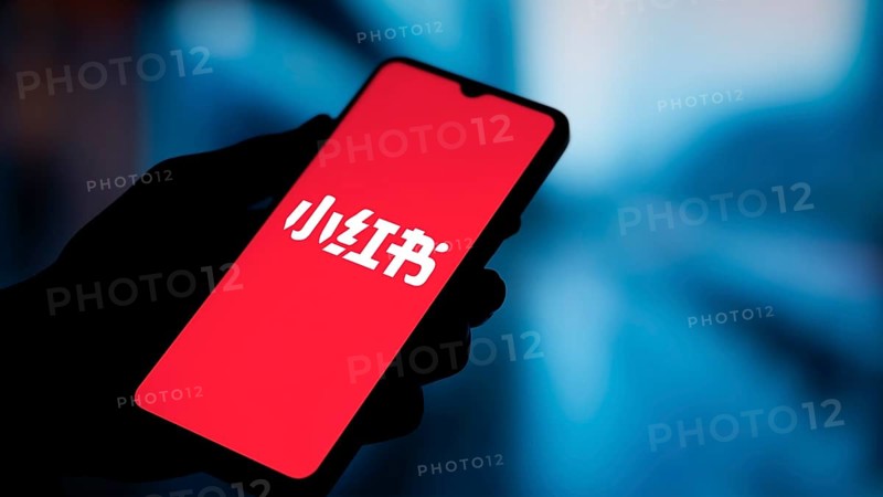 RedNote (Xiaohongshu) logo is displayed on smartphone