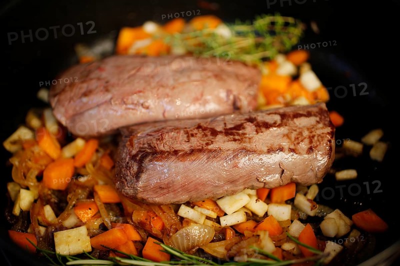Swabian cuisine, preparation of roast venison, game dish, sautéing vegetables, frying pan, carrots, onions, herbs, saddle of venison, meat, grandmother's cooking, regional, home cooking, typical Swabian, traditional cuisine reinterpreted, food photography, studio, Germany
