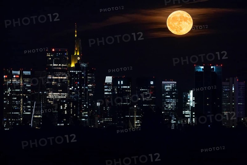The full moon, known as the strawberry moon in June, passes over the Frankfurt banking skyline, Frankfurt am Main, Hesse, Germany