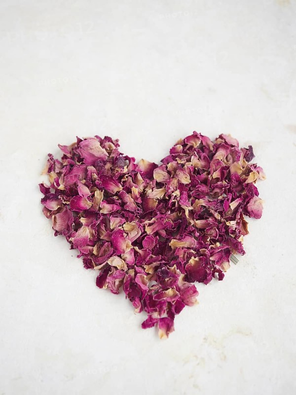 Red heart made of rose petals on beige background. Romantic and love concept for Valentine's Day