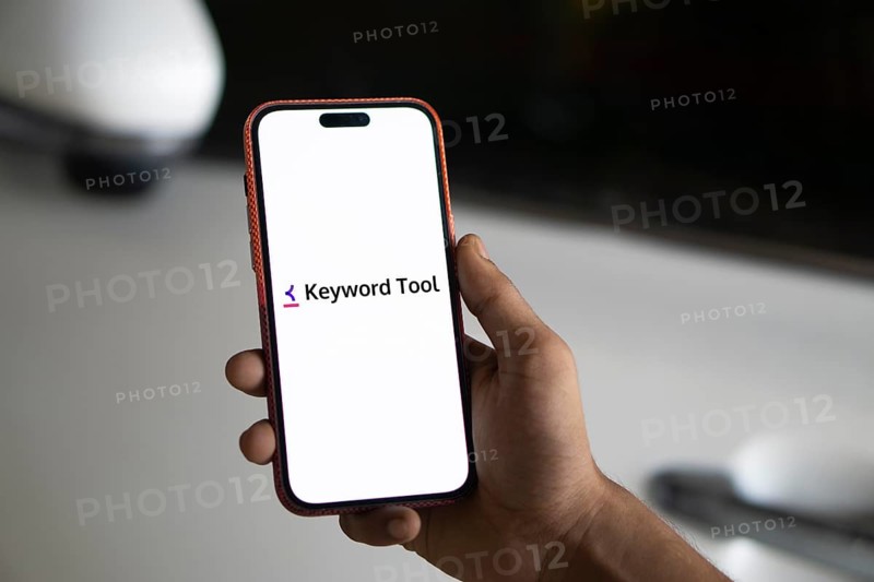 keyword tool logo is displayed on smartphone. Keyword Tool is a free online keyword research tool