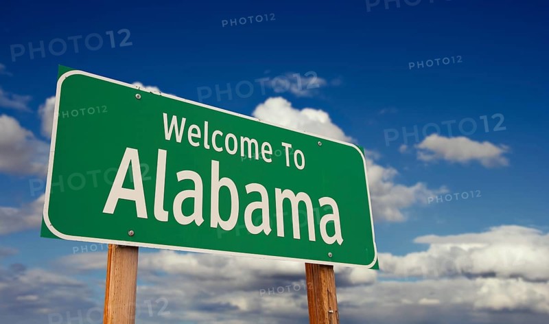 Welcome to alabama green road sign over blue sky with some clouds