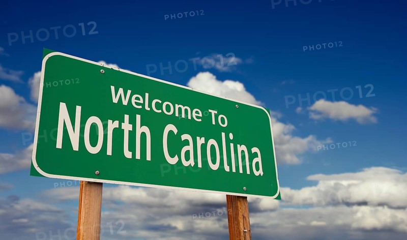 Welcome to north carolina green road sign over blue sky with some clouds