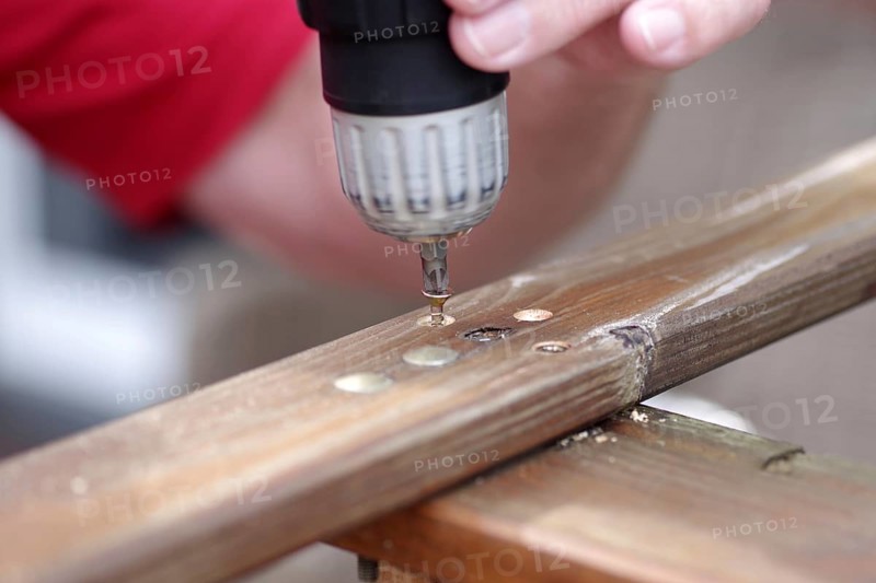 Cordless screwdriver, bit, screw, wood, finger, A screw is turned into the wood with a tool