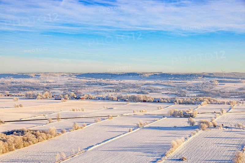 Scenics view at a wintry rural plain landscape with farms and fields a snowy cold winter day, Karleby, Falköping, Sweden