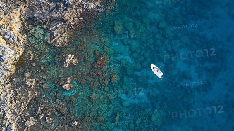 Drone shot, boat in clear blue water next to rocks and corals, Anthony Quinn Bay, Vagies Bay, Rhodes, Dodecanese, Greek Islands, Greece